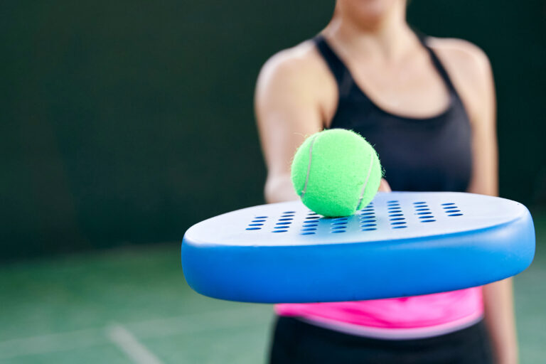 Person holding padel with ball balancing