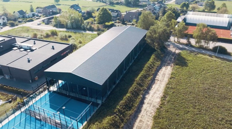 Padel court under enclosed canopy with outdoor courts alongside